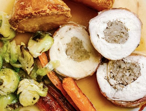 Photograph of Chicken Breast Roast Dinner with Sausages, Roast Potatoes, Roast Carrots, Shredded Brussels Sprouts and Gravy