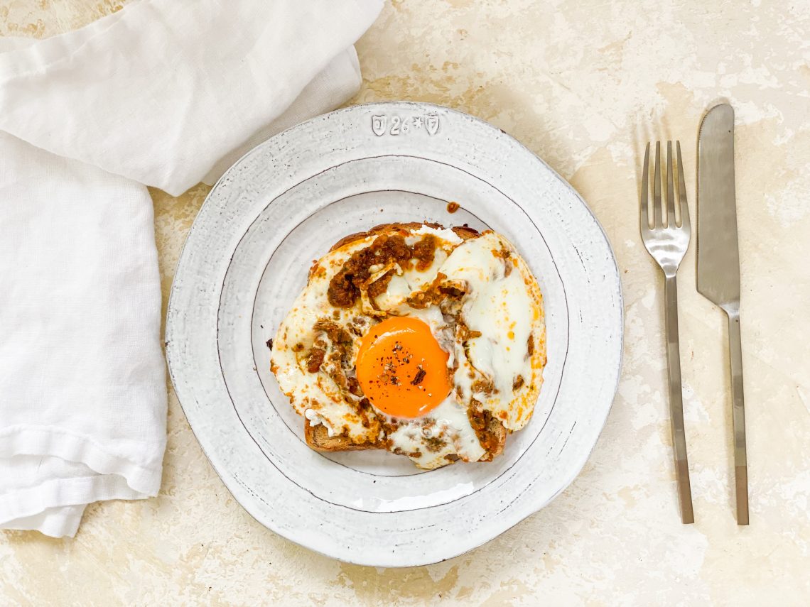 Photograph of Pesto Fried Egg on Toast with Ricotta Cheese and Smoked Chilli Flakes